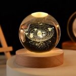 A decorative glass globe featuring a detailed solar system design illuminated with warm light.