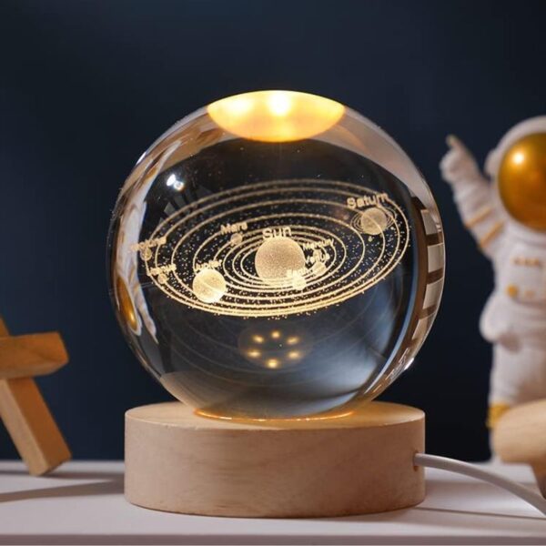 A detailed glass globe showcasing the solar system with planets and their orbits, illuminated with golden accents, mounted on a wooden base.
