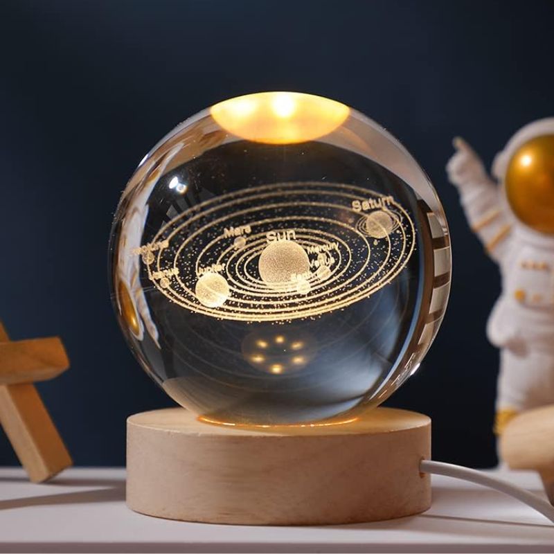 A detailed glass globe showcasing the solar system with planets and their orbits, illuminated with golden accents, mounted on a wooden base.
