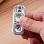 Close-up of a small metallic mechanical component held between fingers, showcasing precise engineering details for science and educational projects.