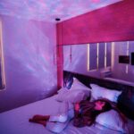 Starry sky projector casting colorful galaxy patterns on bedroom ceiling and walls.