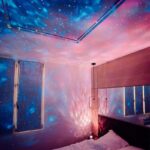Starry sky projector illuminating bedroom ceiling with colorful galaxy and star patterns. Perfect for creating a relaxing, cosmic ambiance in your personal space.