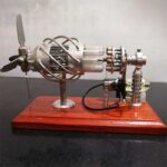 Detailed miniature Tesla coil with metal components and glass tubes, mounted on a polished wooden base.