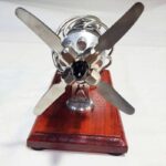 High-speed model helicopter with metal blades and wooden base.