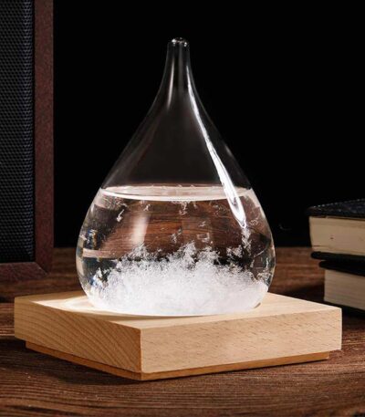 A glass flask with a narrow neck containing a bubbling chemical reaction, placed on a wooden base on a dark background.