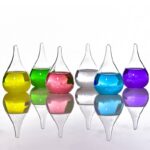 Colorful laboratory glassware with liquids in yellow, green, pink, clear, blue, and purple, reflecting on a smooth surface.