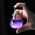 A hand holding a glass flask filled with purple liquid, showcasing a science experiment.