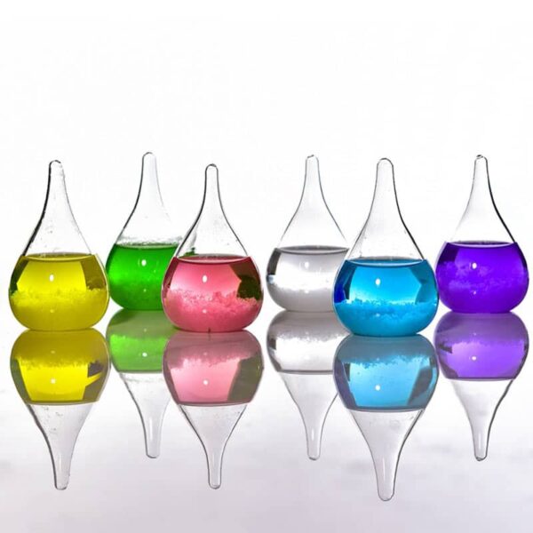 Colorful laboratory glassware with liquids in yellow, green, pink, clear, blue, and purple, reflecting on a smooth surface.