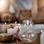 A cozy scene with lit candles and a glass oil diffuser on a wooden surface, creating a relaxing ambiance for home decor and wellness.