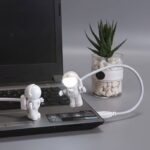 Small astronaut toys interacting with a laptop computer, creating a playful and educational scene.