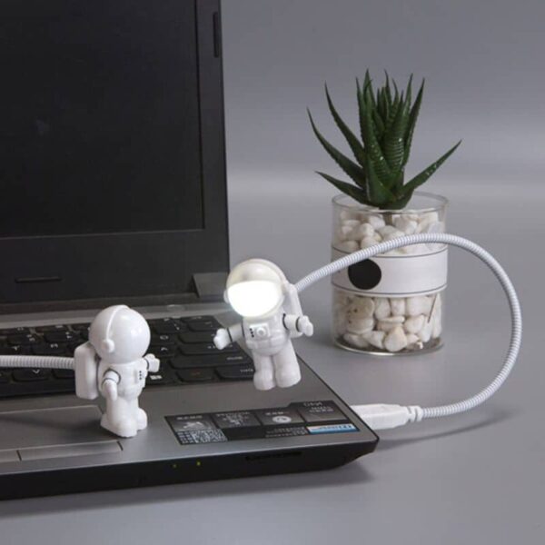 Small astronaut toys interacting with a laptop computer, creating a playful and educational scene.