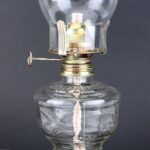 Vintage glass oil lamp with a metal burner and clear glass chimney, ideal for science decor and educational demonstrations.
