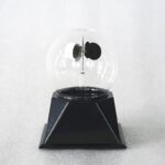 A magnetic globe demonstration model showing magnetic poles and field lines inside a clear glass sphere mounted on a black base.