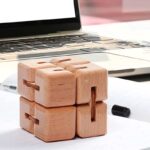 A set of six wooden puzzle cubes stacked on a white surface with a laptop in the background, designed for brain teasers and educational activities.