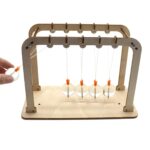 Pendulum science experiment with five glass balls and a wooden frame.