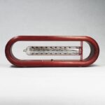 Vintage glass thermometer encased in a red wooden frame, showcasing a classic scientific instrument for temperature measurement.