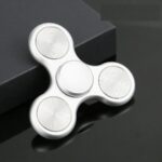 White fidget spinner with three rounded arms and a central bearing, designed for stress relief and focus enhancement.