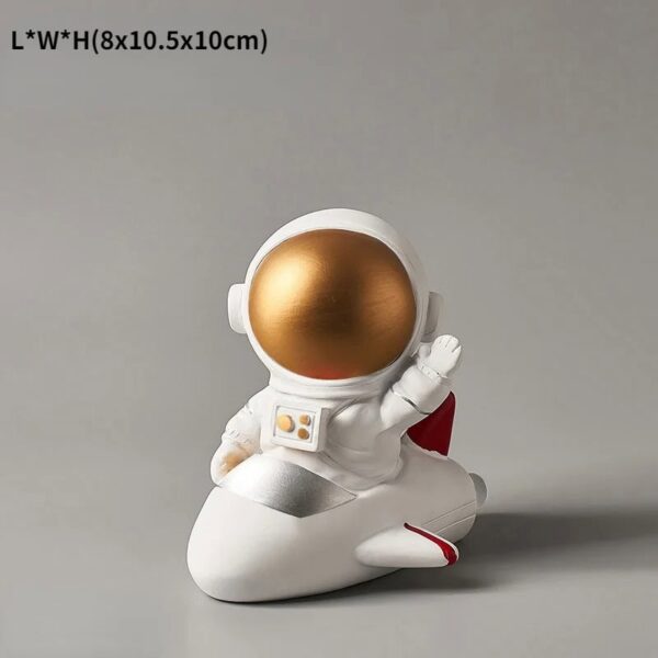 A cute astronaut figurine with a gold helmet, sitting on a white rocket-shaped base, perfect for science-themed decor or educational purposes.