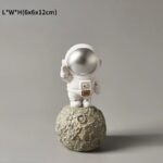 Astronaut figurine standing on a textured moon surface, perfect for science-themed decor and educational displays.