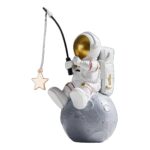Cute astronaut figurine sitting on a moon-shaped base, holding a fishing rod with a star-shaped lure, perfect for space-themed decor and educational toys.