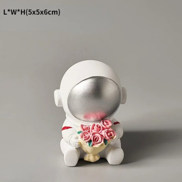 A cute astronaut figurine holding a bouquet of pink roses, designed as a decorative science-themed item.