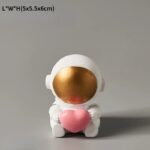 A cute astronaut figurine holding a pink heart, with a white space suit and a shiny gold visor. Perfect for science-themed decor or educational gifts.