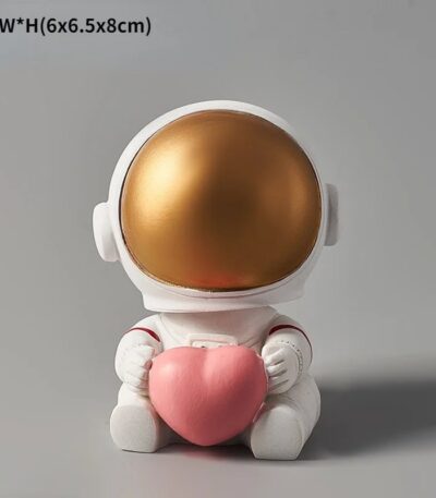 Adorable astronaut figurine holding a pink heart, featuring a shiny gold helmet and white suit, perfect for science-themed decor or educational toys.