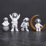 Astronaut figurines set featuring four space explorers in white suits with reflective helmets, accompanied by a crescent moon prop, perfect for science decor and educational toys.