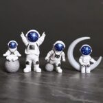 Set of four astronaut figurines with blue starry helmets, sitting on moon and planet-shaped bases, perfect for science decor and educational toys.