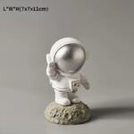 A cute astronaut figurine with a reflective helmet, standing on a textured moon-like base. Perfect for science decor or educational displays related to space exploration.