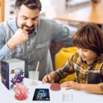A father and son engaging with science experiment kits at a table, exploring colorful mineral specimens and educational gadgets.