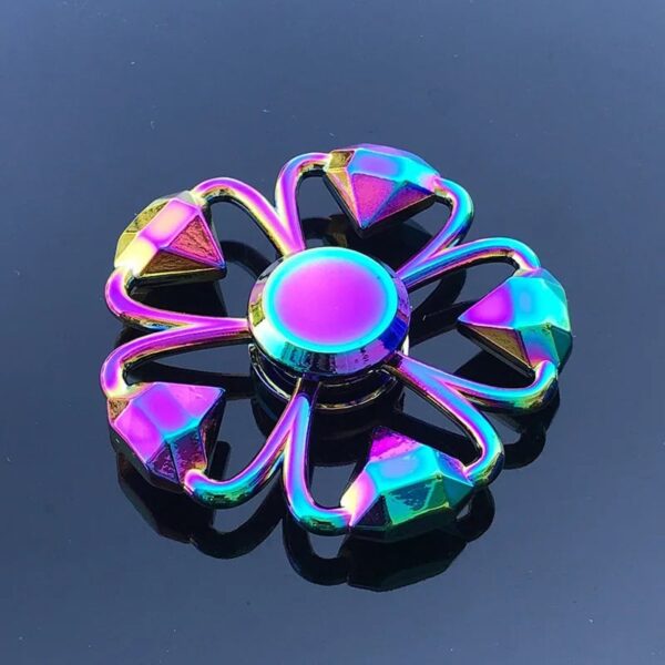 A vibrant, rainbow-colored flower-shaped fidget spinner with a central bearing, designed for stress relief and sensory stimulation.