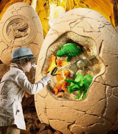 Child excavating colorful dinosaur toys from a large fossil replica egg in a themed educational play area.