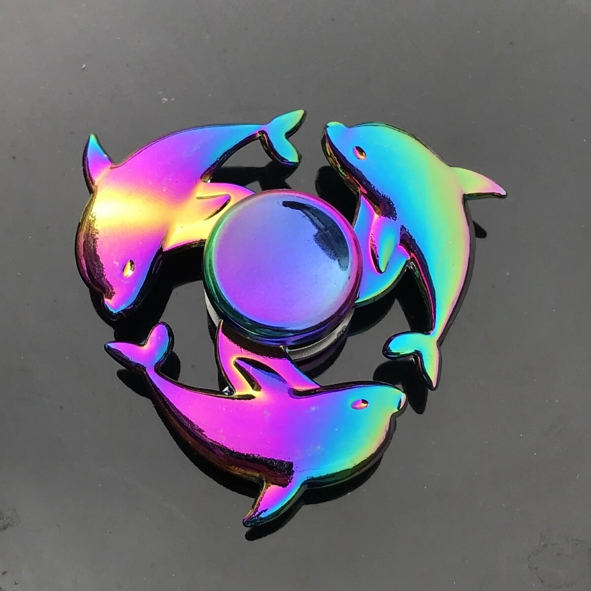 Shiny Dolphin Fidget Spinner Set Colorful dolphin-shaped fidget spinner set with a central ball, made of iridescent material, designed for stress relief and sensory play.