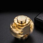 Gold fidget spinner spinning rapidly on a dark surface, showcasing its smooth motion and metallic finish.