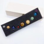 Colorful marble set with nine glass marbles in a black foam display case, ideal for educational and decorative purposes.