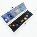 A set of nine miniature planets representing the solar system, displayed in a white case with a foam insert, ideal for educational purposes and space-themed decor.