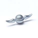 A shiny silver spherical toy with detailed wing designs on each side, resembling a small flying object or gadget. Perfect for science decor or educational displays.