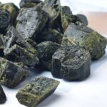Close-up of dark green and black mineral rocks with mossy patches, ideal for science education and geology projects.