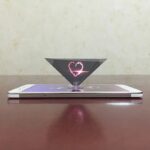 Laser heart projection floating above smartphone screen.