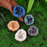 Colorful geode-shaped candle holders with glitter accents on green moss background.