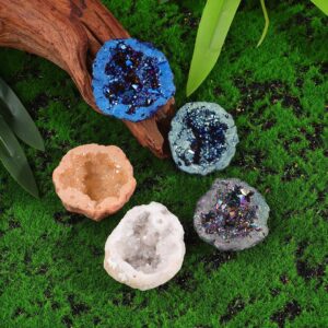Colorful geode-shaped candle holders with glitter accents on green moss background.