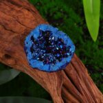 Blue geode mineral specimen with sparkling crystals on a wooden surface, ideal for educational purposes and home decor.