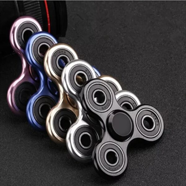 Colorful fidget spinners in various metallic finishes arranged on a dark surface, showcasing their smooth design and spinning capability.