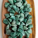 Collection of green fluorite crystal stones arranged on a wooden surface, used for healing, meditation, and decorative purposes.