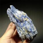 Hand holding a large blue kyanite crystal with a textured surface, ideal for healing, meditation, and energy work.