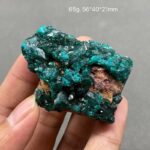 A close-up of a vibrant green fluorite crystal mineral held between fingers, showcasing its natural crystalline structure and vivid color.