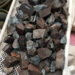 Assorted natural stones in a white basket, ideal for science decor and educational toys.