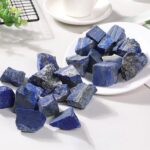 Natural lapis lazuli mineral stones with deep blue color and gold pyrite inclusions, displayed on a white surface for educational and decorative purposes.