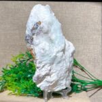 Close-up of a white quartz crystal mineral specimen on a stand, showcasing its natural crystalline structure, ideal for science, decor, and educational purposes.